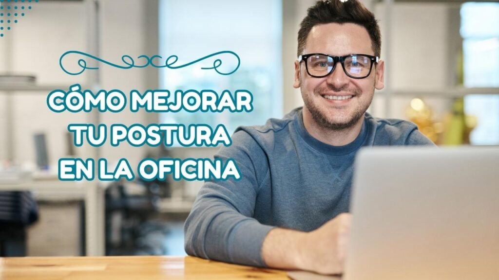 Hombre sentado en escritorio frente a su portátil mirando a la cámara mientras sonríe