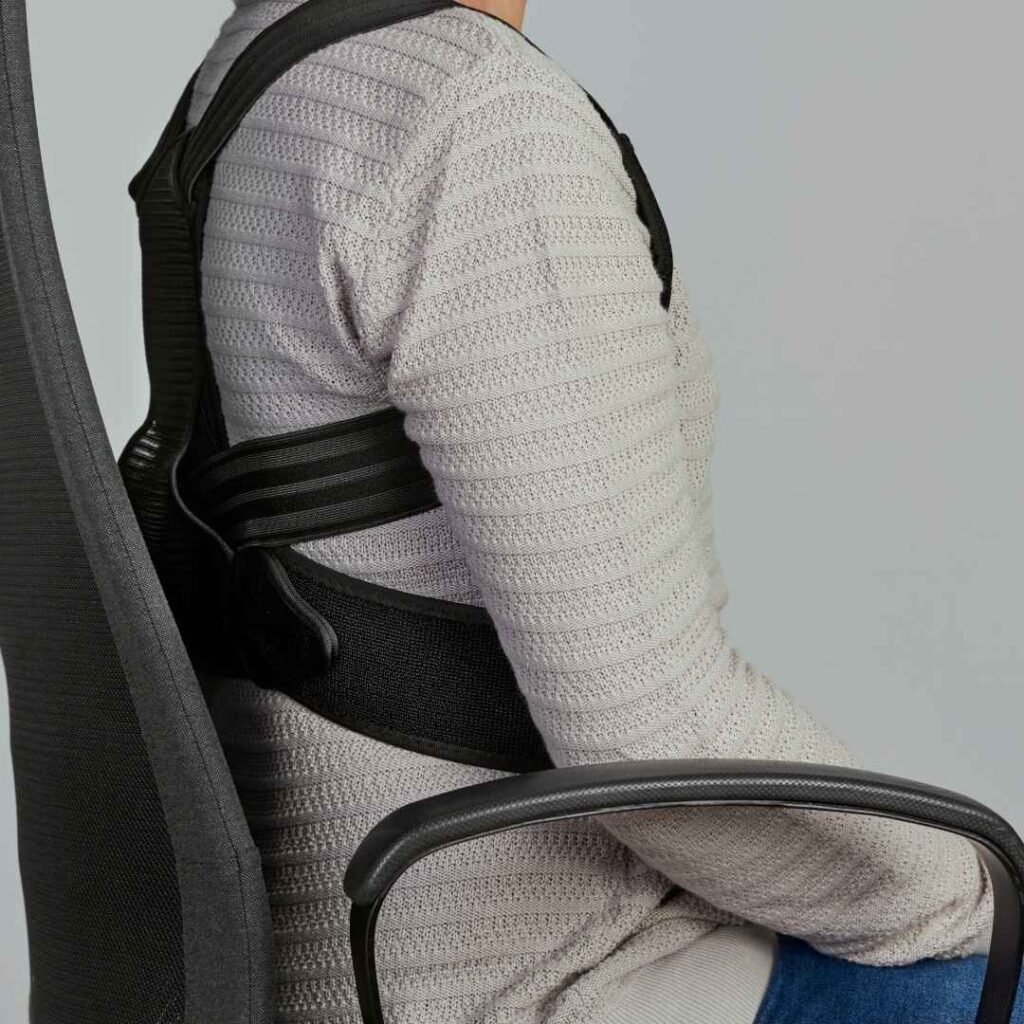 hombre sentado en silla de oficina con un corrector postural puesto