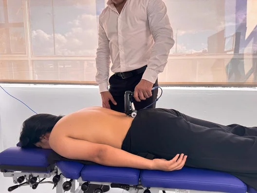 quiropráctico realizando escaneo en la columna vertebral de su paciente