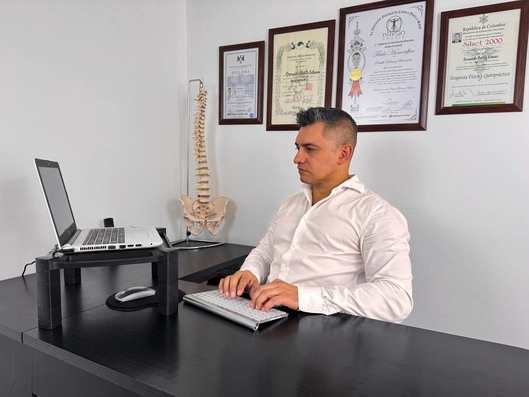 Quiropráctico sentado en su silla trabajando en su computador